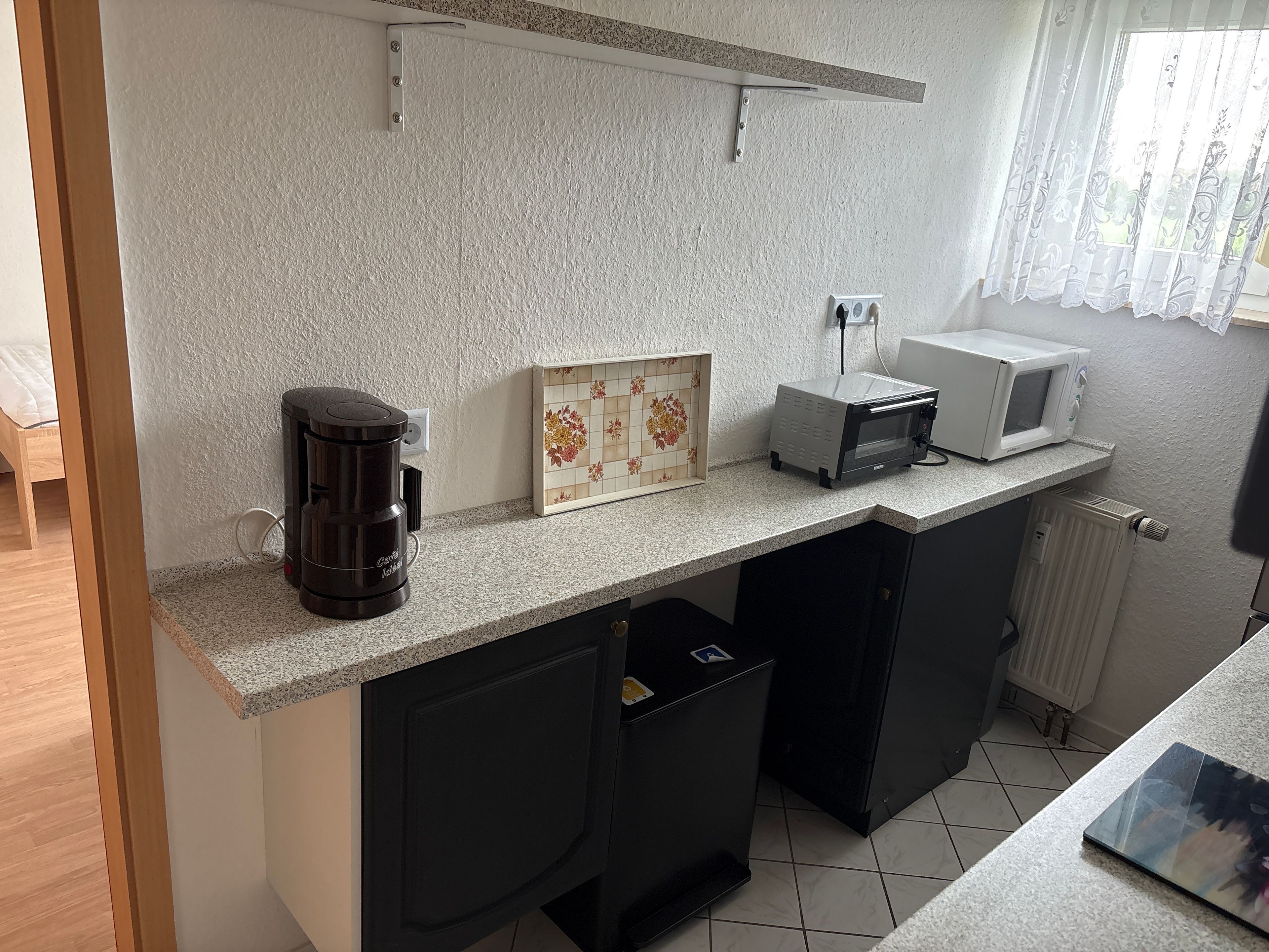 Una cocina compacta con cafetera, microondas y salpicadero de azulejos.