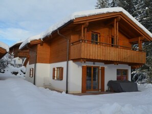 Eine Holzhütte mit Balkon, umgeben von Schnee.