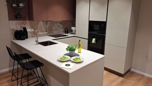 Een moderne keuken met een centraal eiland, een bar met barkrukken, een inbouwoven en een magnetron.