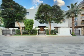 A building with a central entrance, surrounded by trees and a paved area. - Cozy Corner at Elevens by spacey #27 (cairo)