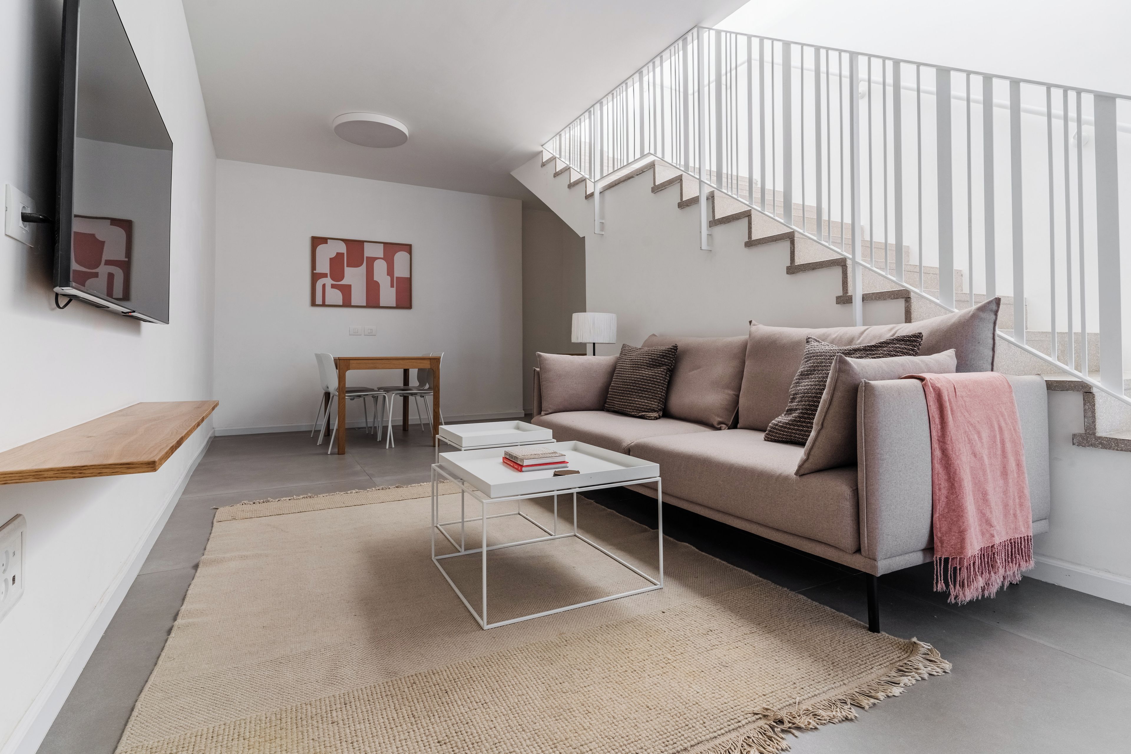 En moderne stue med sofa, sofabord og trappe.
