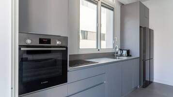 Een moderne keuken met een Bosch oven, een roestvrijstalen koelkast en een raam dat voor natuurlijk licht zorgt.