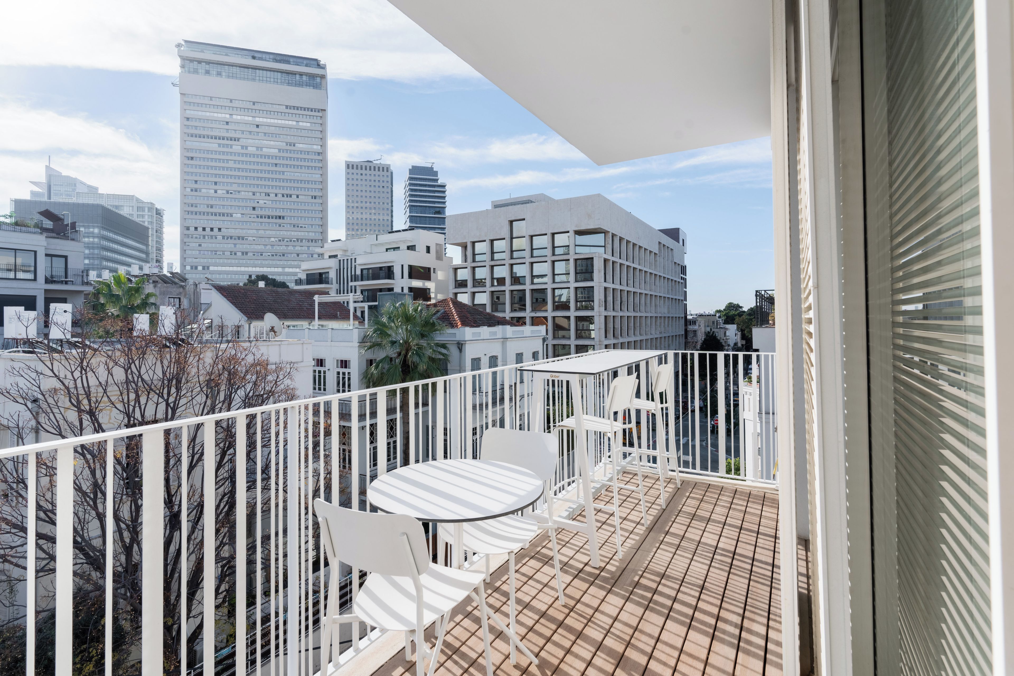 Een balkon met uitzicht op een stadsgezicht, met moderne gebouwen en een heldere lucht.