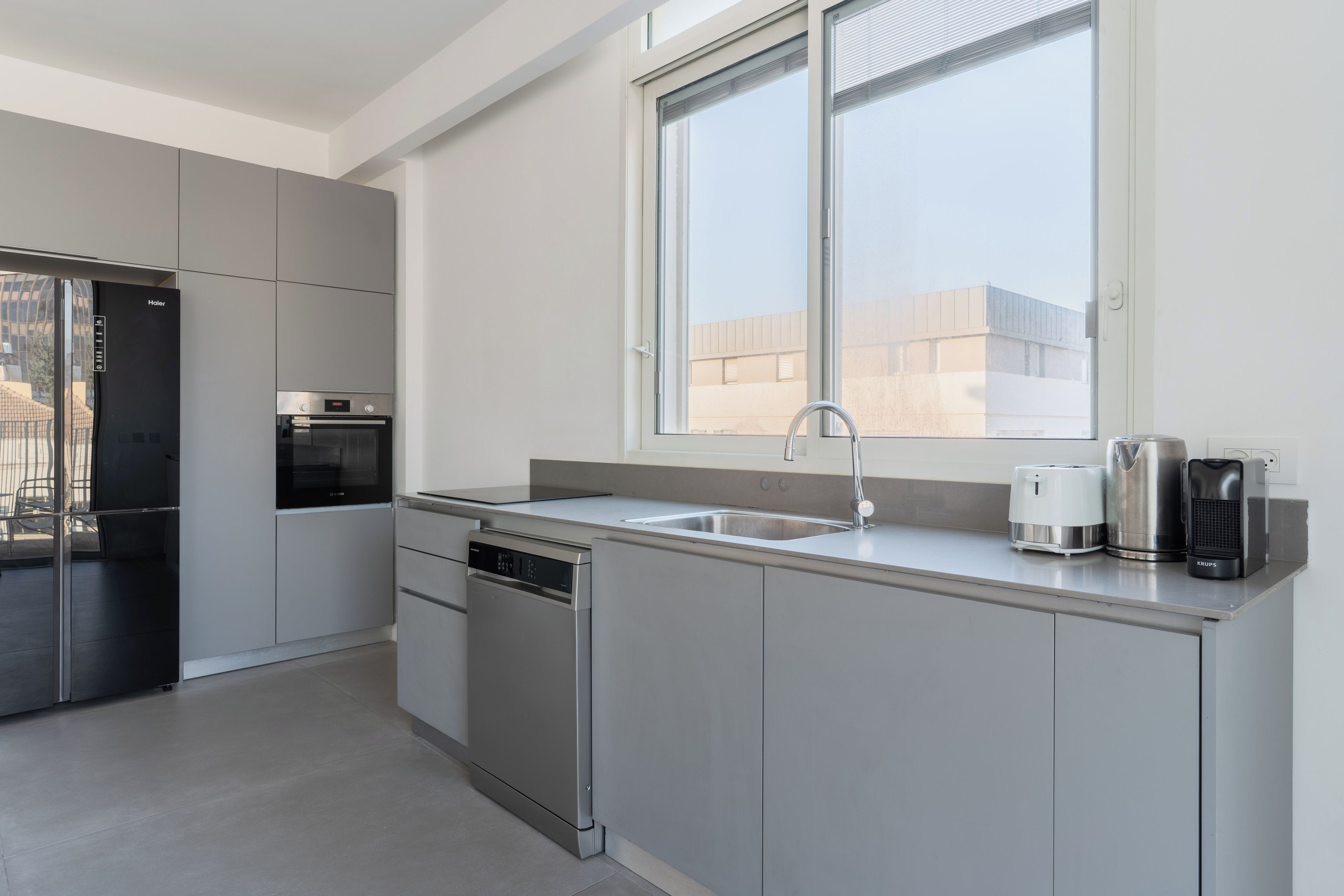 A modern kitchen with stainless steel appliances, a dishwasher, and a window above the sink.