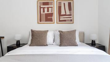 A hotel room with a bed, two nightstands, a lamp, and abstract artwork on the wall.
