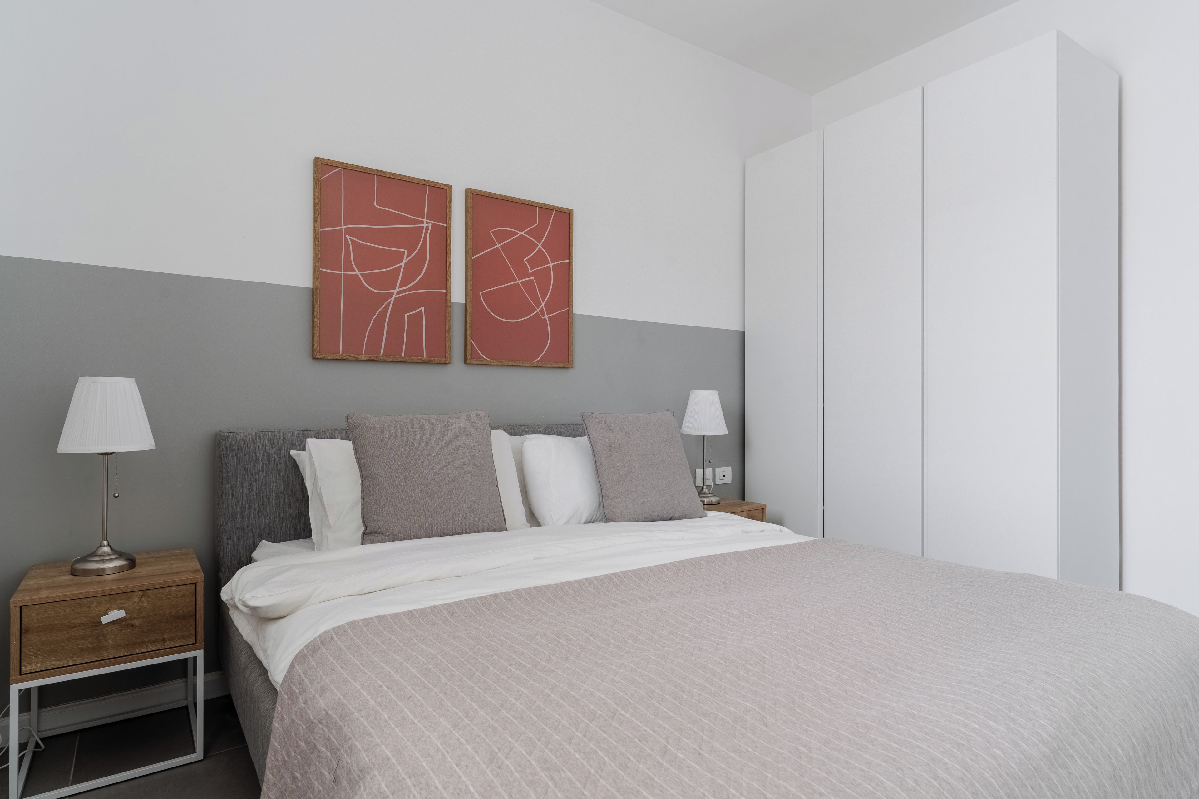 A modern bedroom with a bed, two bedside tables, a nightstand, and abstract wall art.