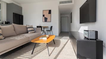 A modern living room with a sofa, coffee table, and a flat-screen TV mounted on the wall.