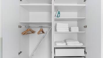 A white closet with shelves, a hanging rod, and a metal rack.