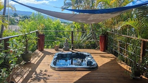 A hot tub on a wooden deck with a view of a lush garden and distant hills. - Beautiful vacation villa 🌴 (Le Tampon)