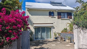 A two-story house with a garage, surrounded by lush greenery and flowering plants. - Beautiful vacation villa 🌴 (Le Tampon)