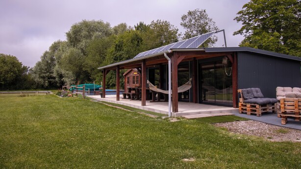 A rustic cabin with a covered patio, solar panels, and outdoor seating. - Vrbo Property (Brutelles)
