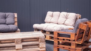 A wooden bench and a sofa made from pallets, positioned against a dark wall. - Vrbo Property (Brutelles)