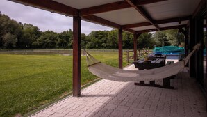 A hammock under a covered area with a view of a grassy field and trees. - Vrbo Property (Brutelles)
