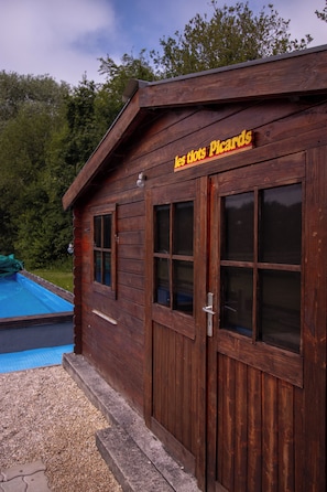 Eine Holzhütte mit einem Schild, auf dem 'les tiots Picards' steht, und einem Pool im Hintergrund.