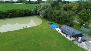 A large green field with a swimming pool, a covered outdoor seating area, and a small boat docked by the water. - Vrbo Property (Brutelles)