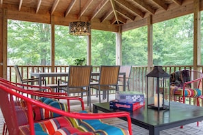 A covered outdoor seating area with wooden furniture, a table, and a lantern. - Charming Saugatuck retreat less than a mile from downtown with nature preserve views. (Saugatuck)