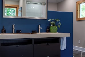 A bathroom with a double sink, a mirror, a green plant, and a towel rack. - Charming Saugatuck retreat less than a mile from downtown with nature preserve views. (Saugatuck)