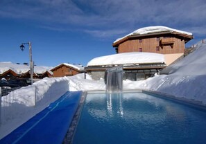A pool with a wooden building in the background. - Apartment for 6 People in Valmeinier (Valmeinier)