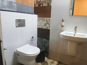 A small bathroom with a toilet, a sink, and a trash bin. - Townhouse Technopark Phase 1 (Thiruvananthapuram)