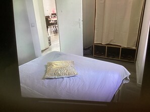 A room with a bed, a door leading to another room, and a curtain. - Apartment in the heart of the village, in a quiet location, with a panoramic view. (Forcalquier)