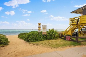 A beach path with signs, a lifeguard tower, and a clear view of the ocean. - ¼ mile to Kam I Beach, Renovated 3BR Resort apt (Kihei)
