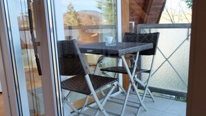 A glass door leading to an outdoor seating area with a table and two chairs. - Vrbo Property (Freiburg im Breisgau)