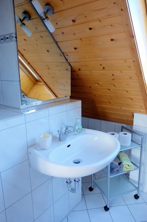 A bathroom with a white sink, a mirror, and a wooden ceiling. - Cozy vacation rental in Freiburg-Lehen, top floor with a beautiful view (Freiburg im Breisgau)