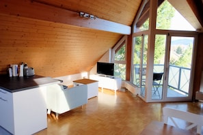 Eine moderne Küche mit Holzboden, großen Fenstern und Blick ins Grüne.