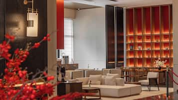 A modern lobby with a seating area, a fireplace, and a bookshelf.
