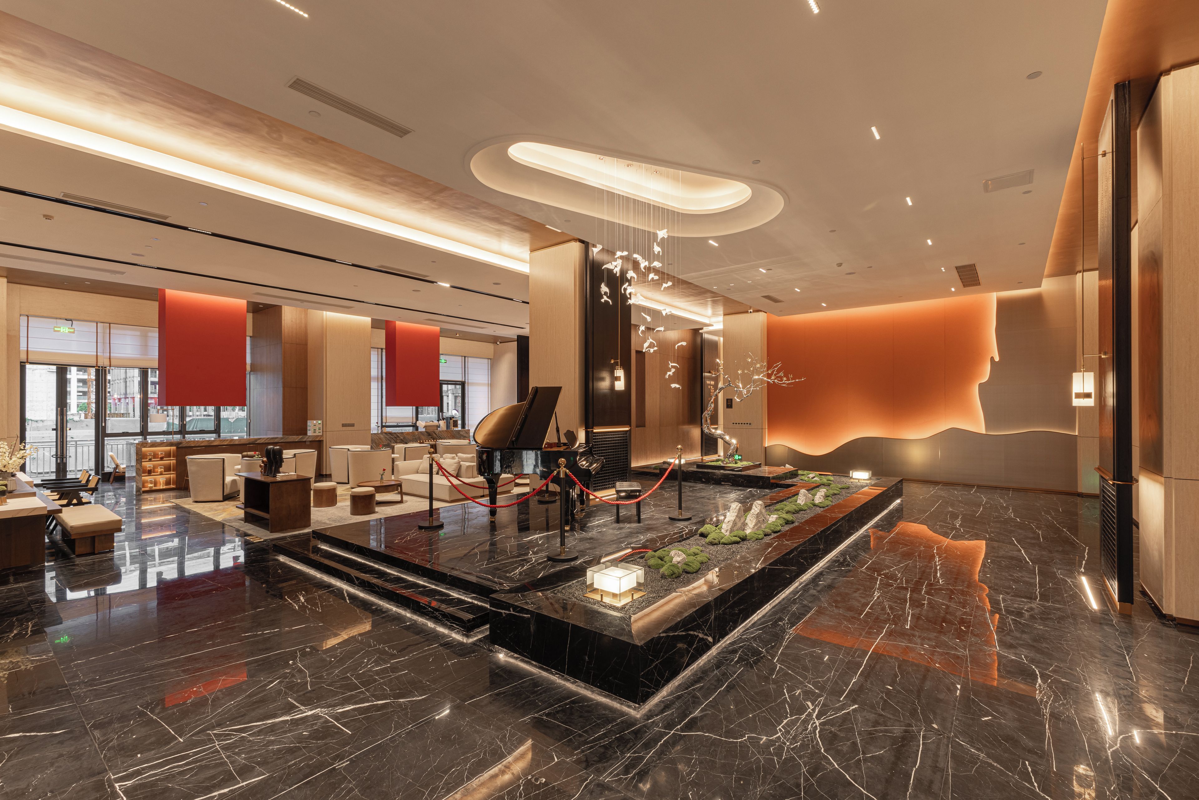 A modern lobby with a grand piano, seating area, and a reception desk.