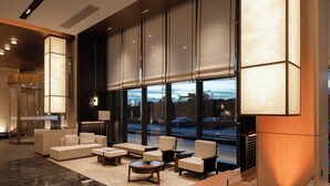 Eine moderne Lobby mit einer Couch, Sesseln, einem Couchtisch und einem großen Fenster mit Blick auf die Straße.