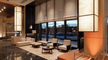 A modern lobby with a sofa, chairs, a coffee table, and a large window with a view of the street.