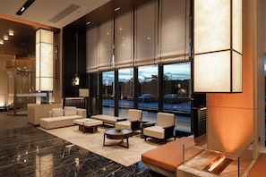Eine moderne Lobby mit einer Couch, Sesseln, einem Couchtisch und einem großen Fenster mit Blick auf die Straße.