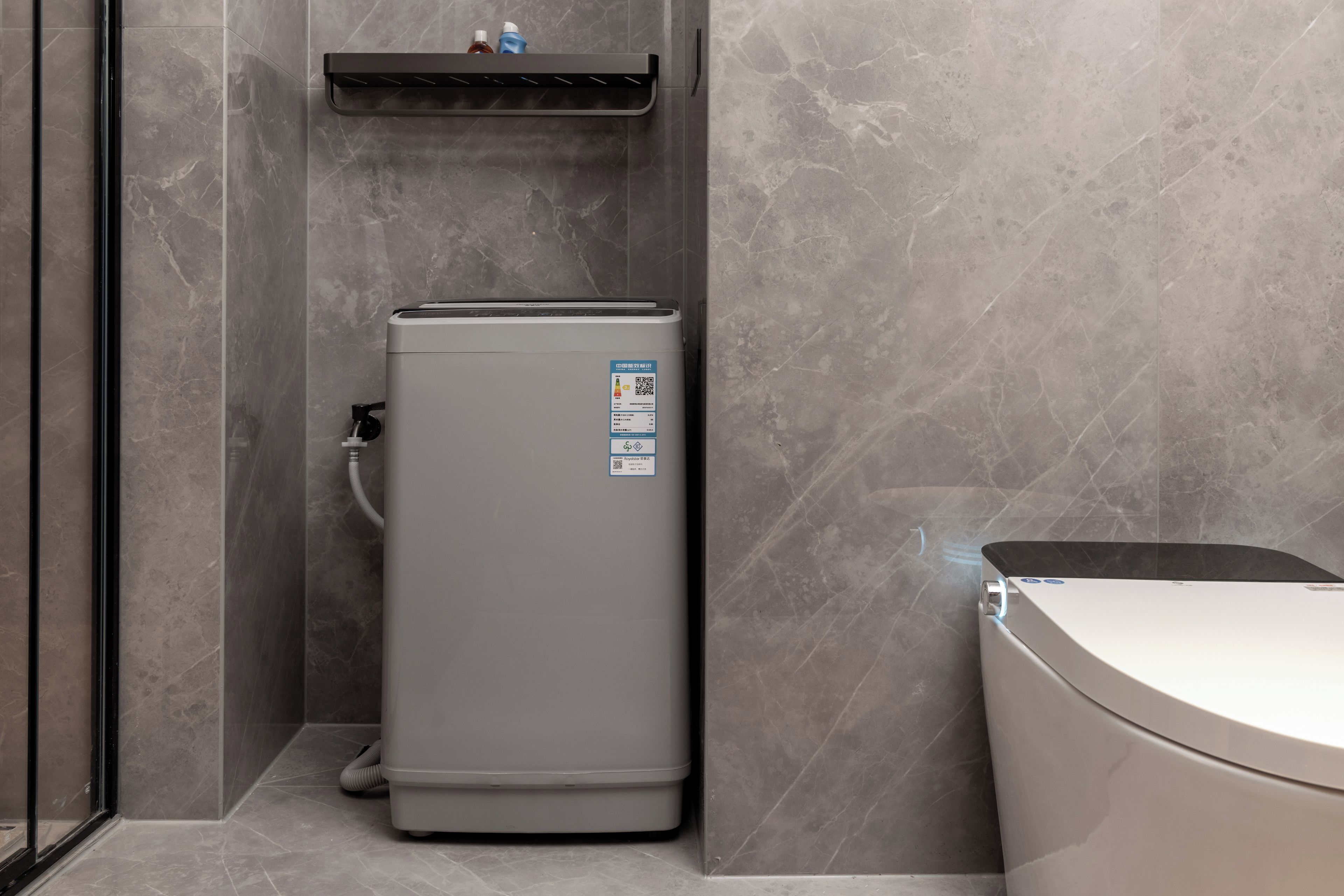 A compact, modern bathroom with a grey water heater, a toilet, and a built-in sink.