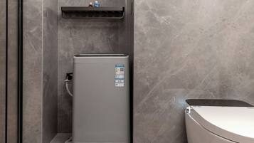 A compact, modern bathroom with a grey water heater, a toilet, and a built-in sink.