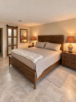 A bedroom with a wooden bed, two bedside tables with lamps, a mirror, and a wardrobe.