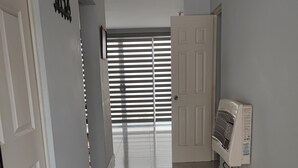 Ein Flur mit einer Tür, einer Wandklimaanlage und einem Fenster mit Jalousien.