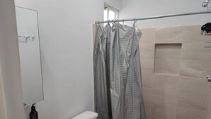 Ein Badezimmer mit Toilette, Waschbecken, Duschvorhang und gefliesten Wänden.
