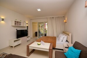 Ein modernes Hotelzimmer mit Bett, Fernseher, Schreibtisch und einem Balkon mit Vorhängen.