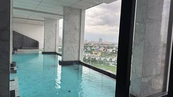 Une piscine intérieure avec vue sur la ville, des colonnes en marbre et un design moderne.