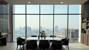 Un comedor moderno con una mesa grande y sillas, ventanas amplias con vistas a la ciudad y una decoración minimalista.