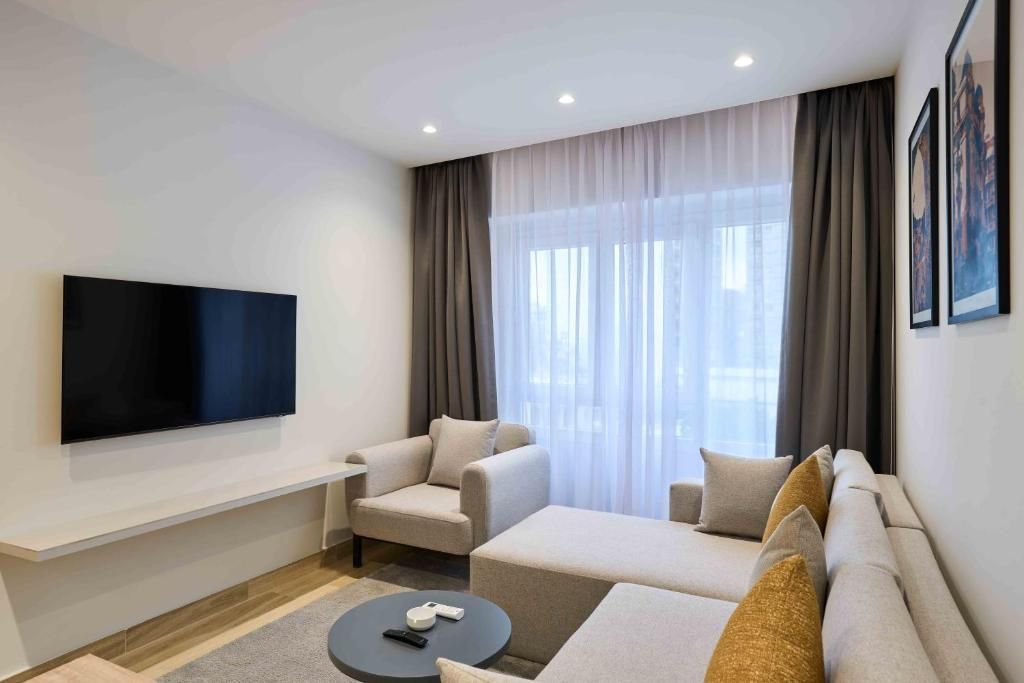 A modern living room with a flat-screen TV, a sofa, a chair, and a coffee table.