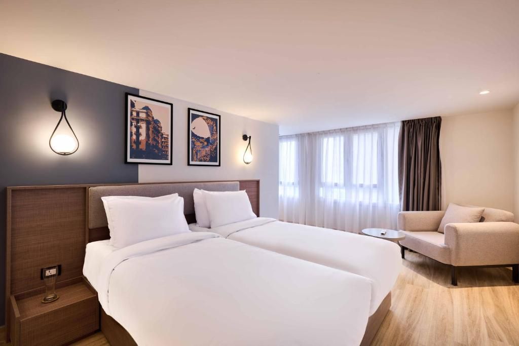 Een hotelkamer met twee bedden, een bank, een klein tafeltje en kunst aan de muur.