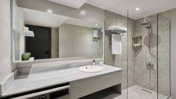 Un baño moderno con un espejo grande, un lavamanos y una zona de ducha con paredes de vidrio.