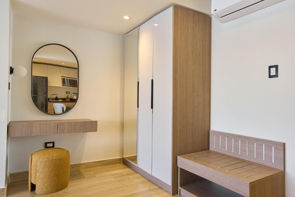 Een moderne kamer met een houten bankje, een ronde spiegel, een kledingkast en een klein krukje.
