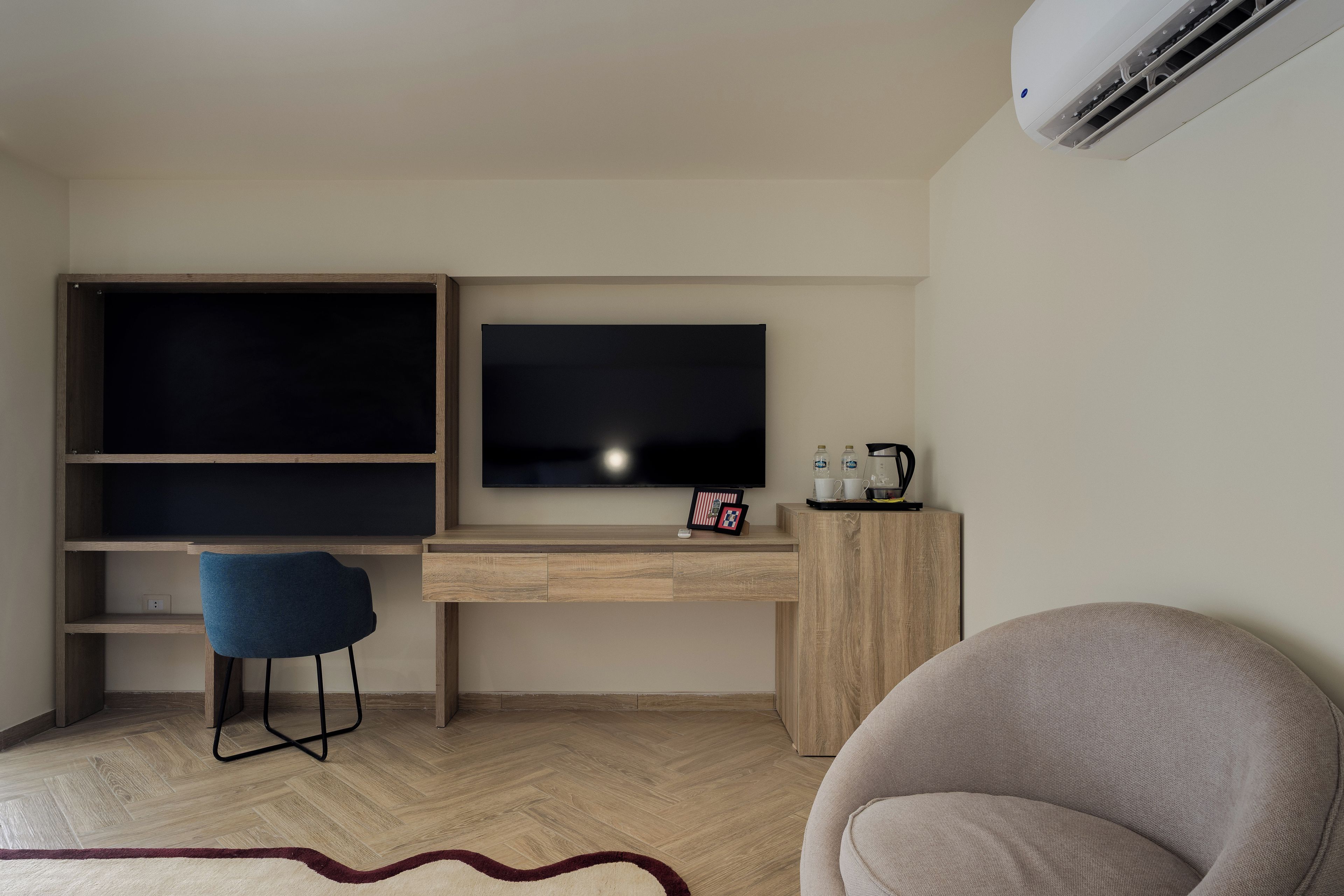A modern room with a wooden desk, a television, a chair, and a sofa.