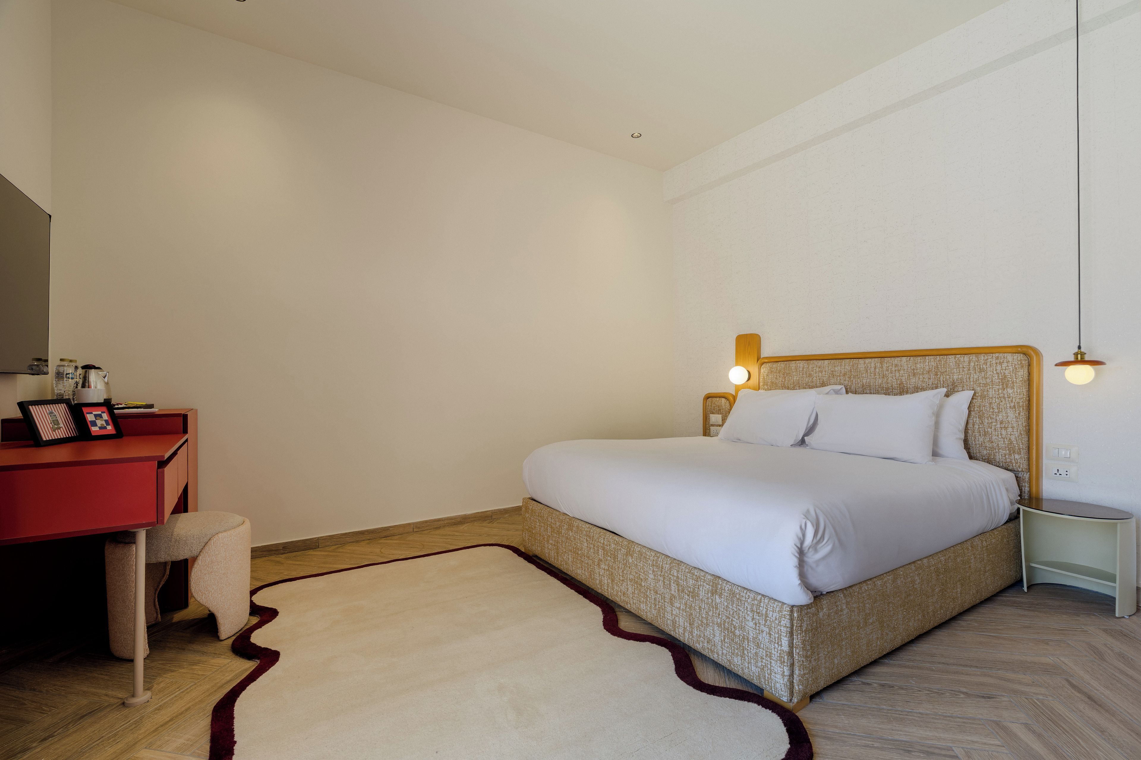 A bedroom with a bed, a desk, a chair, and a nightstand.