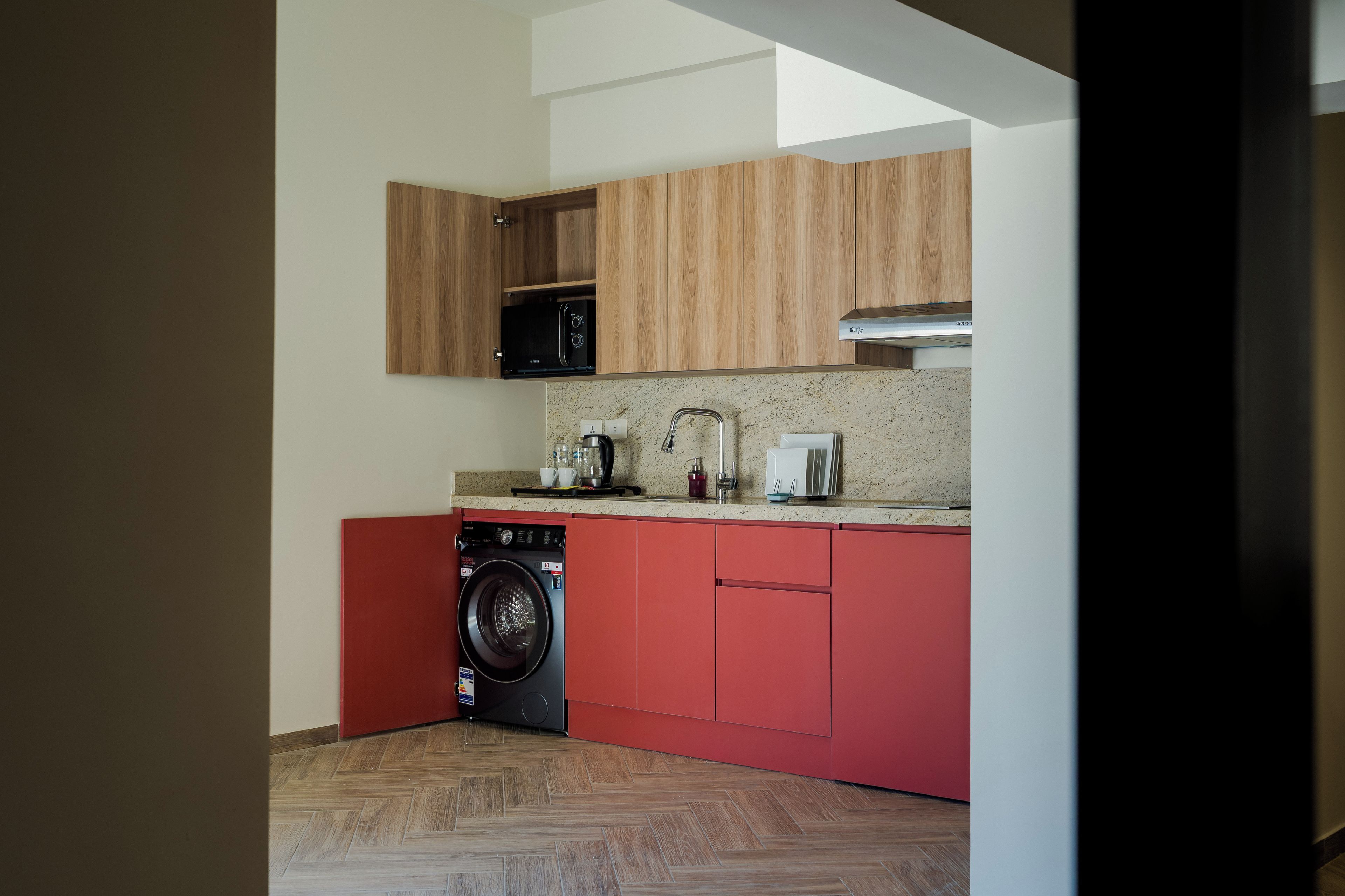 A compact kitchen with wooden cabinets, a microwave, a coffee maker, and a dishwasher.