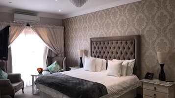 Una camera d'albergo con un letto grande, un comodino, una sedia e una lampada decorativa.