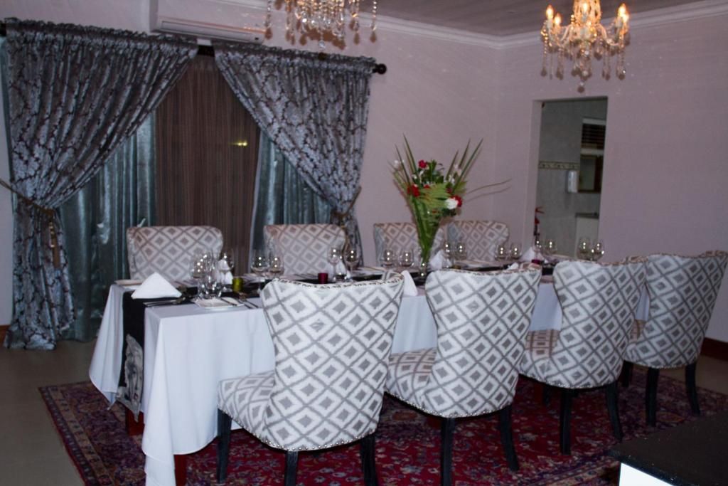 Comedor con mesa dispuesta para cuatro, sillas estampadas, un jarrón de flores y una araña.